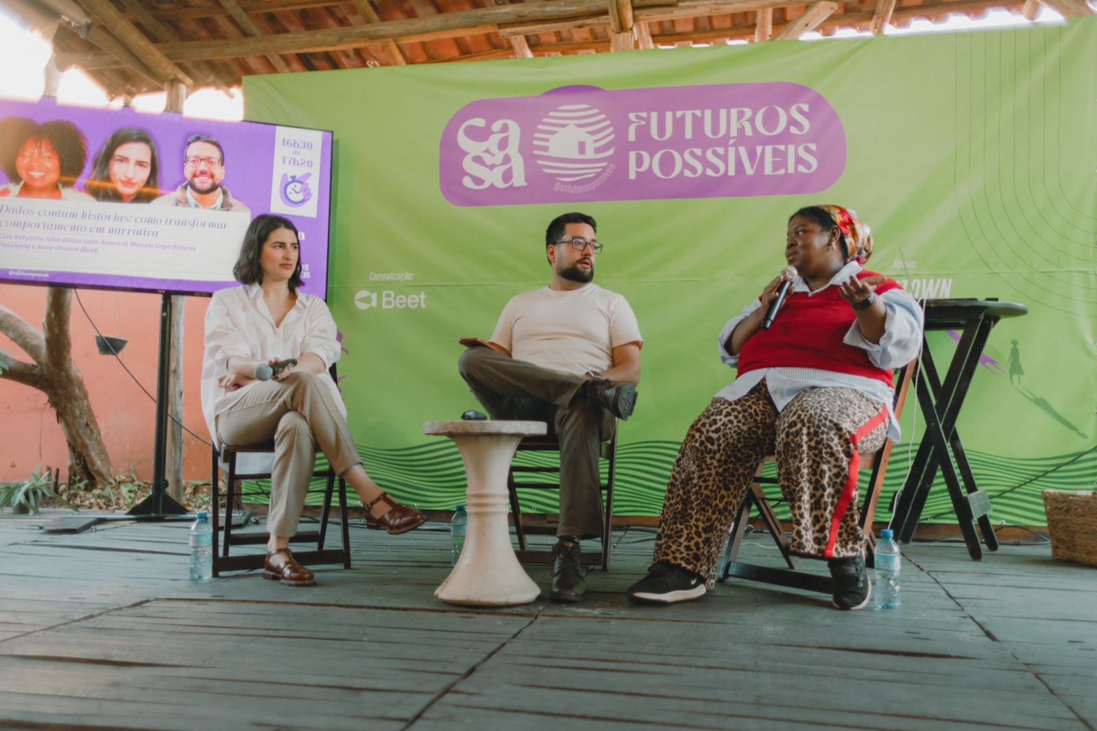 Ketyanne falando ao microfone em um painel na Casa Futuros Possíveis, ao lado de dois painelistas